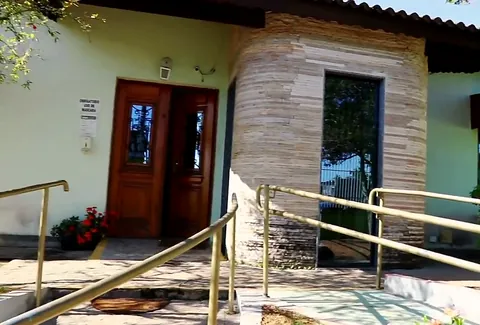 Porta de madeira da entrada do Residencial, com rampa de acesso e flores
