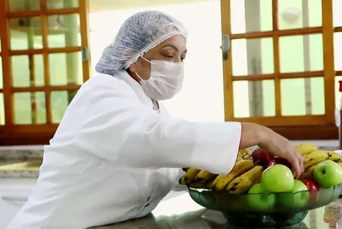 Profissional da cozinha prepara a fruteira com bananas e maçãs